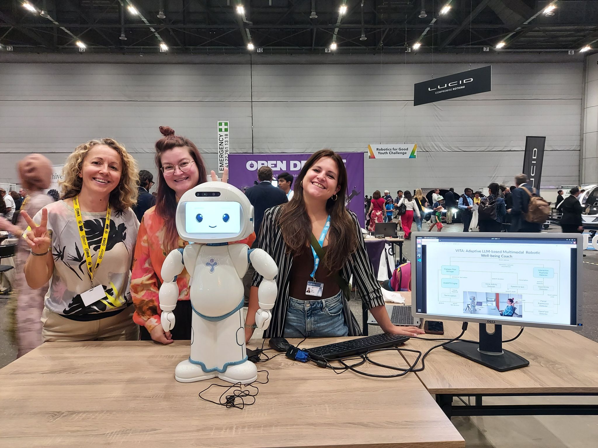 Three women behind a white plastic child-shaped robot.